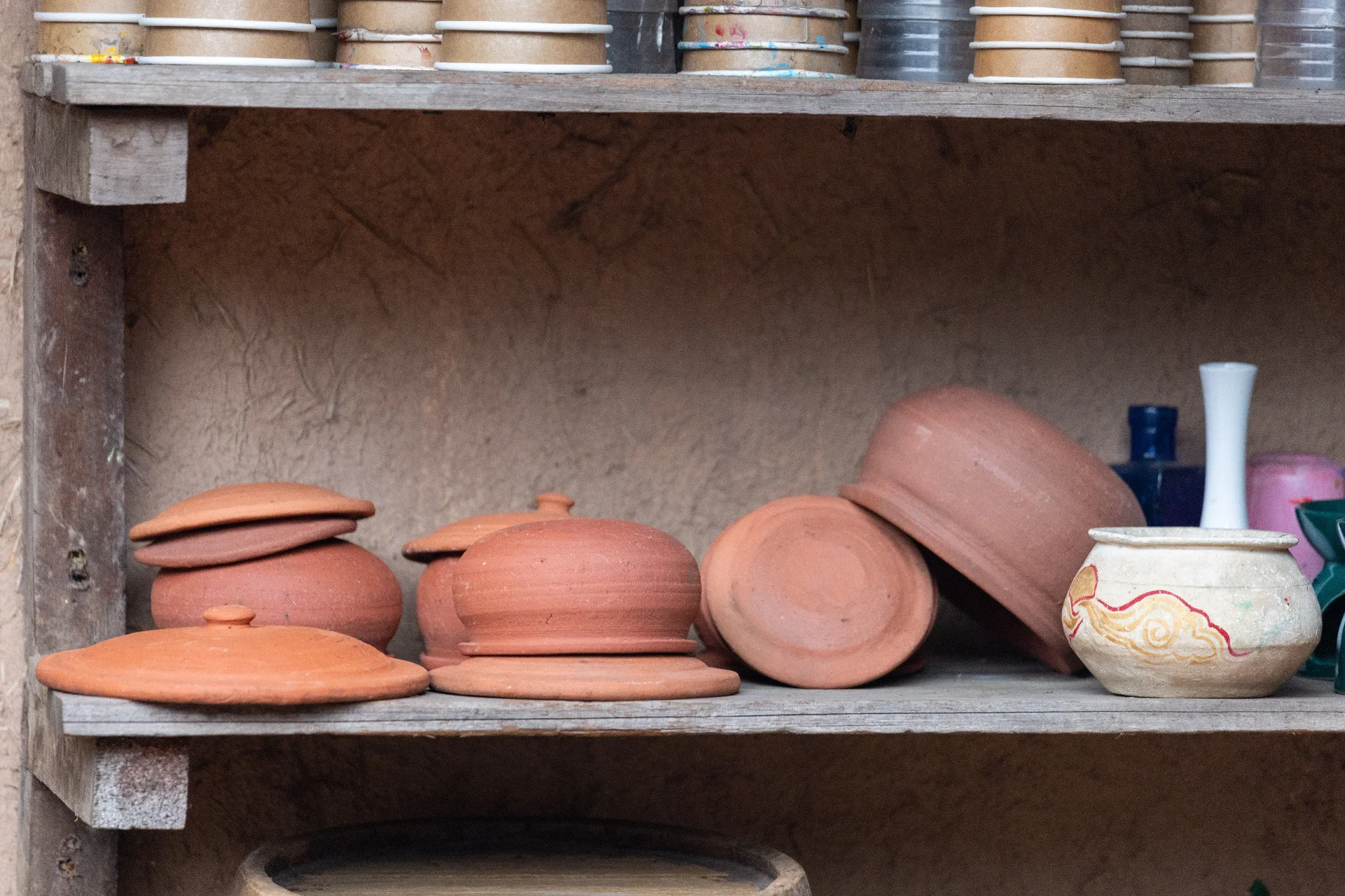 A collection of traditional clay pots on a rustic wooden shelf.