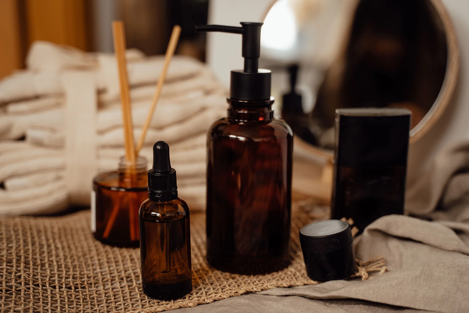 Rustic brown bottle display with cosmetics and essential oils on burlap indoors.